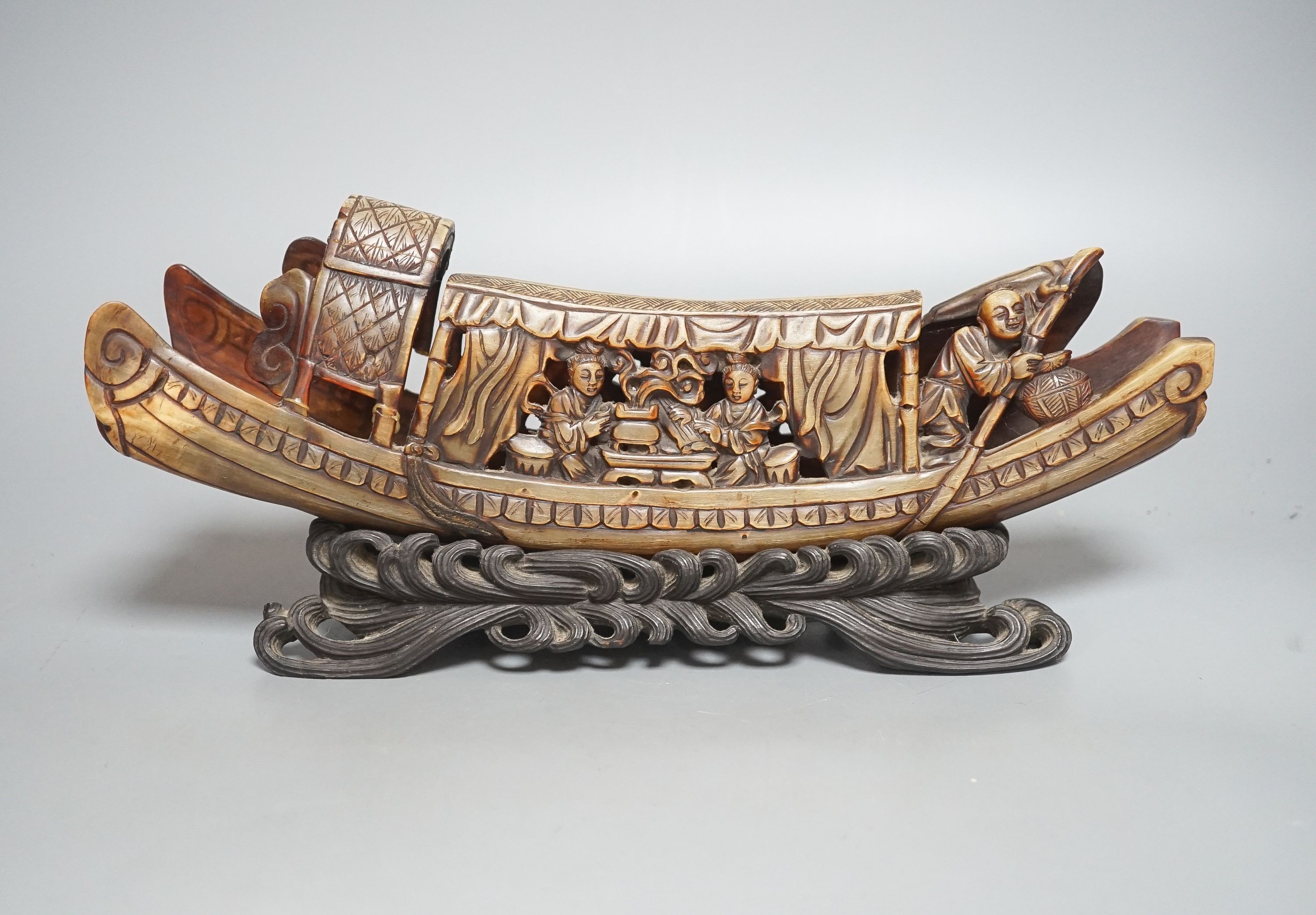 A Chinese horn carving of a junk boat, wood stand, 34cm